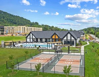 A pickleball court is surrounded by a grassy area and a building in the background.